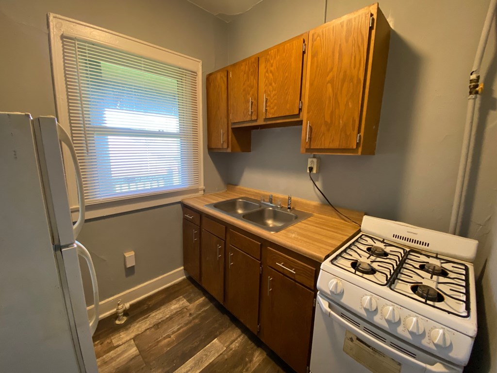 A kitchen with a white stove and wooden cabinets.