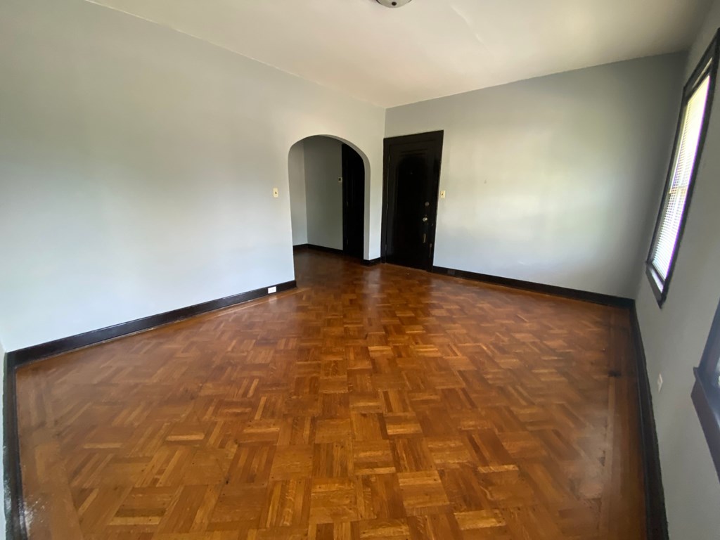 A room with a wooden floor and two arched doorways.