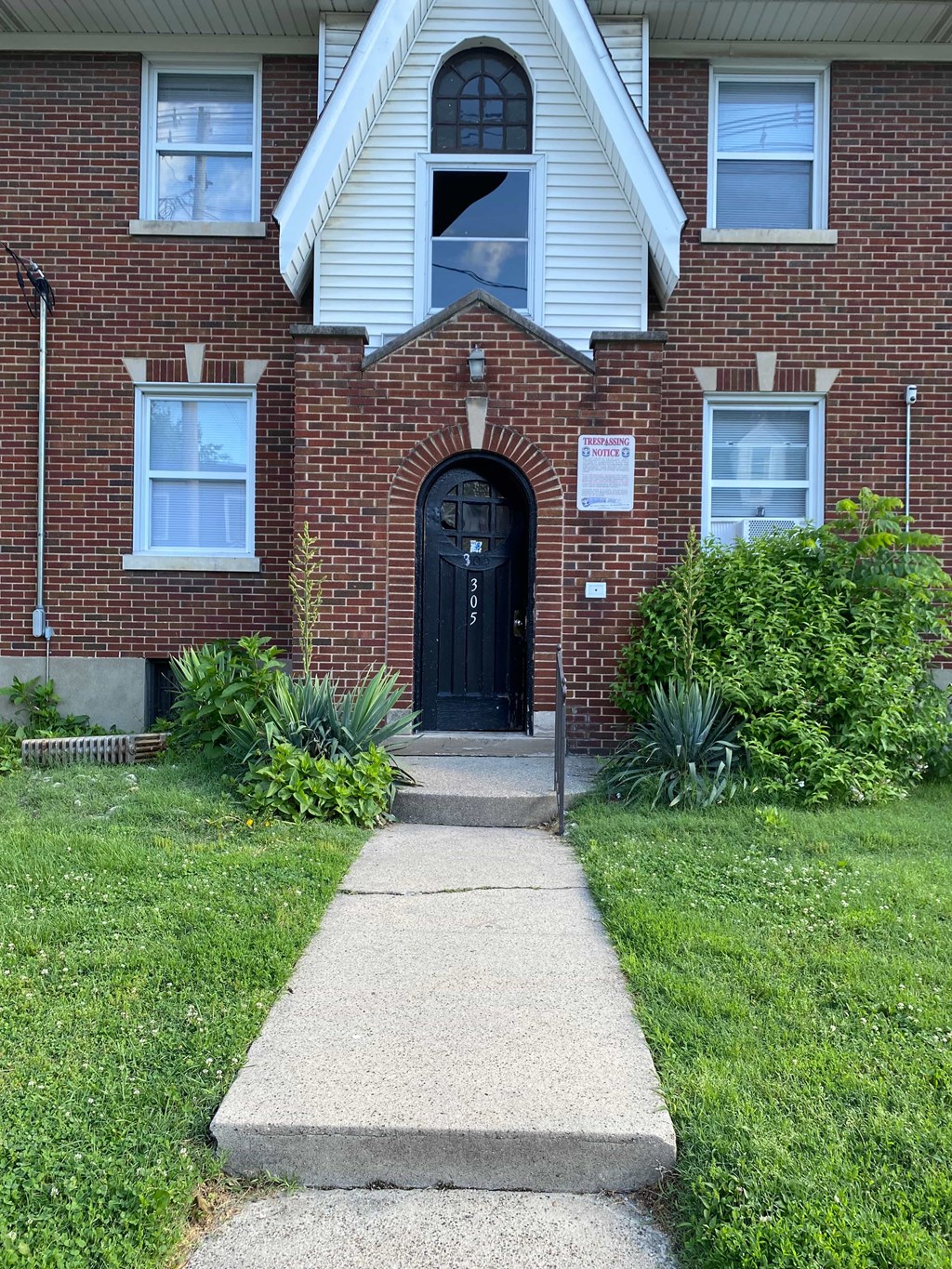 A brick house with a black door and a sign on the front.