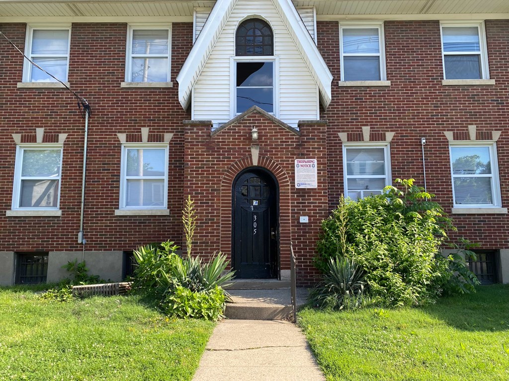 A red brick building with a black door and a sign on the front.