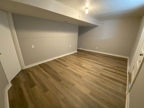 A room with wooden flooring and white walls.