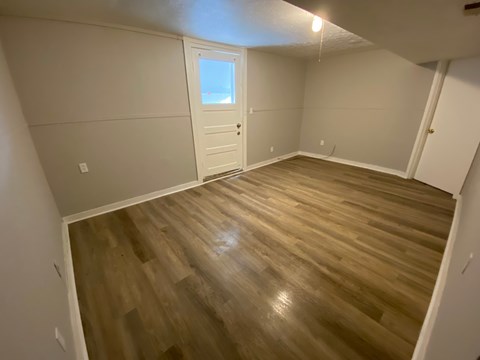 A room with wooden flooring and a white door.