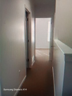 A long hallway with white walls and a brown floor.
