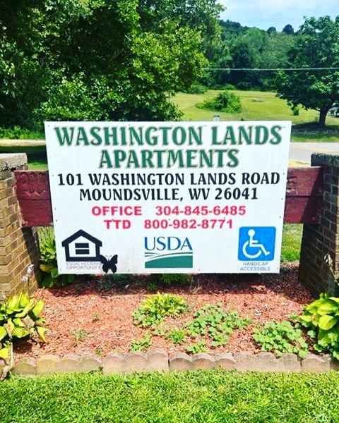 A sign for Washington Lands Apartments with contact information and a USDA logo.