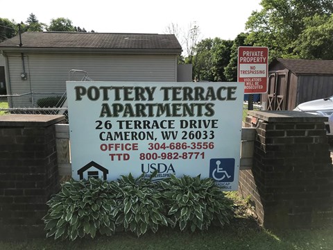 A sign for Pottery Terrace Apartments is displayed in front of a building.