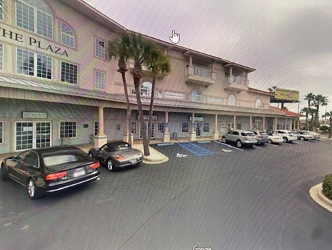 A black car is parked in front of a building with a sign that says "The Plaza.".