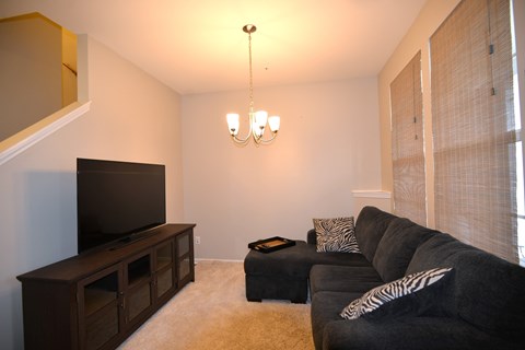 A living room with a black couch and a television.