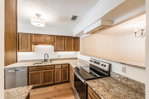 A kitchen with wooden cabinets and granite countertops.