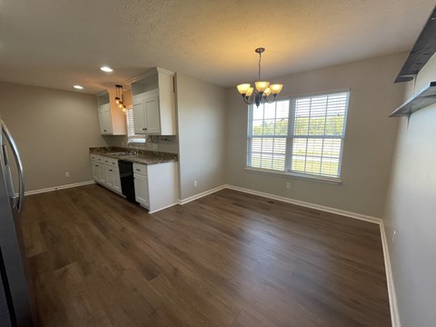 A kitchen with white cabinets and a wooden floor.
