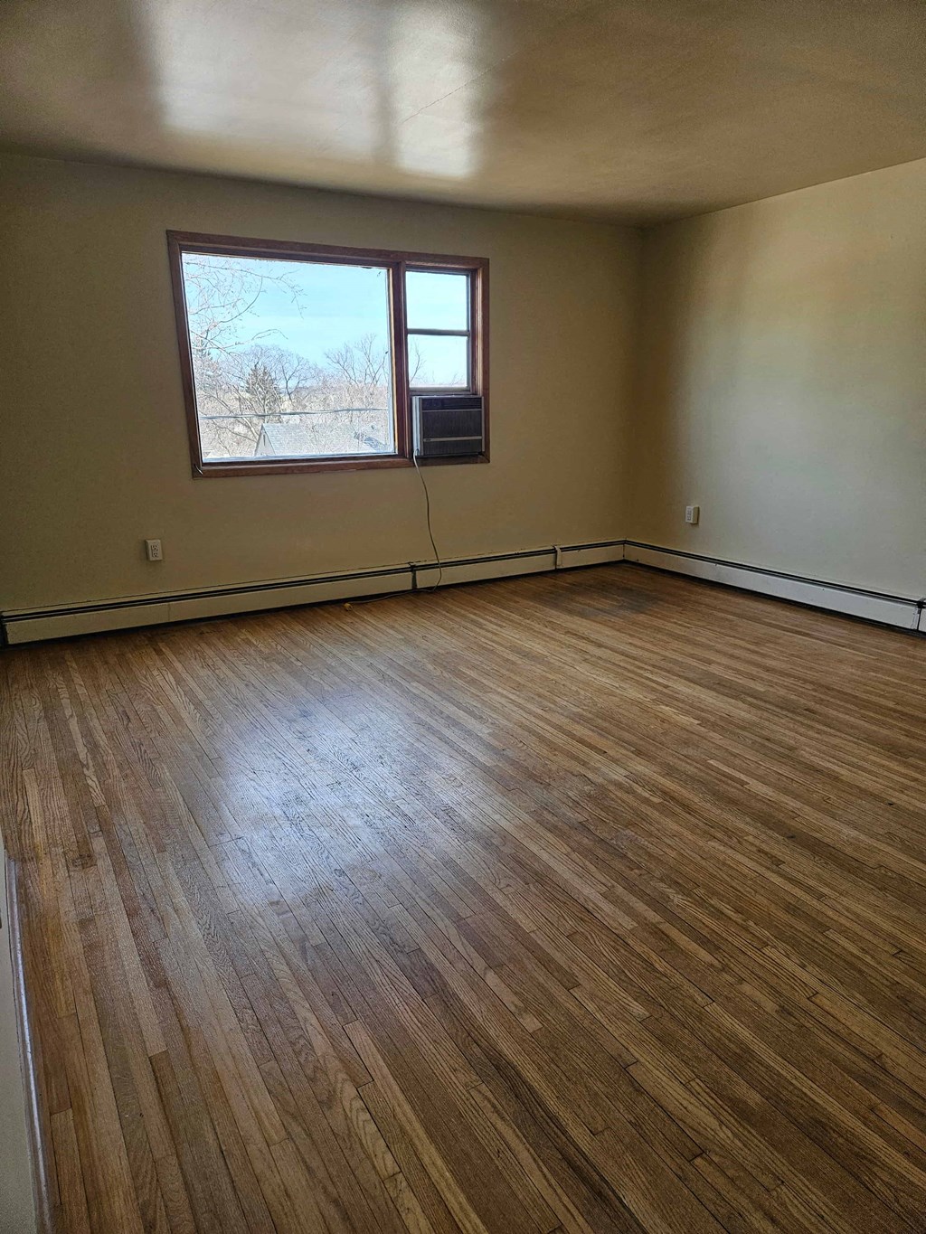 A room with wooden flooring and a window.