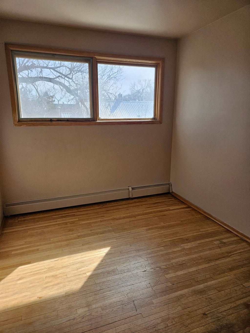 A room with a window and wooden flooring.