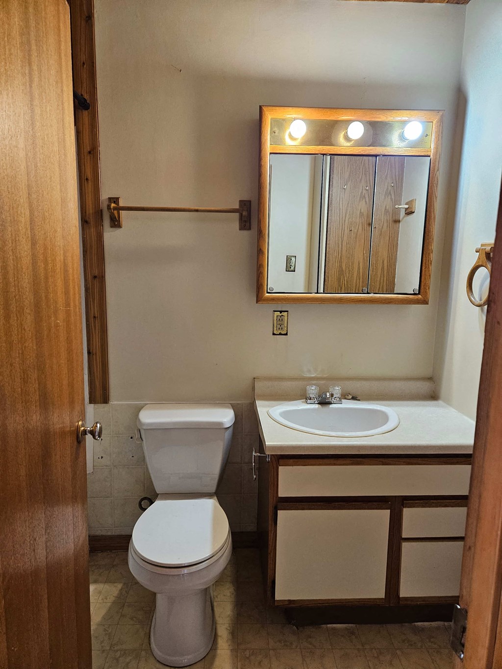 A bathroom with a toilet, sink and mirror.