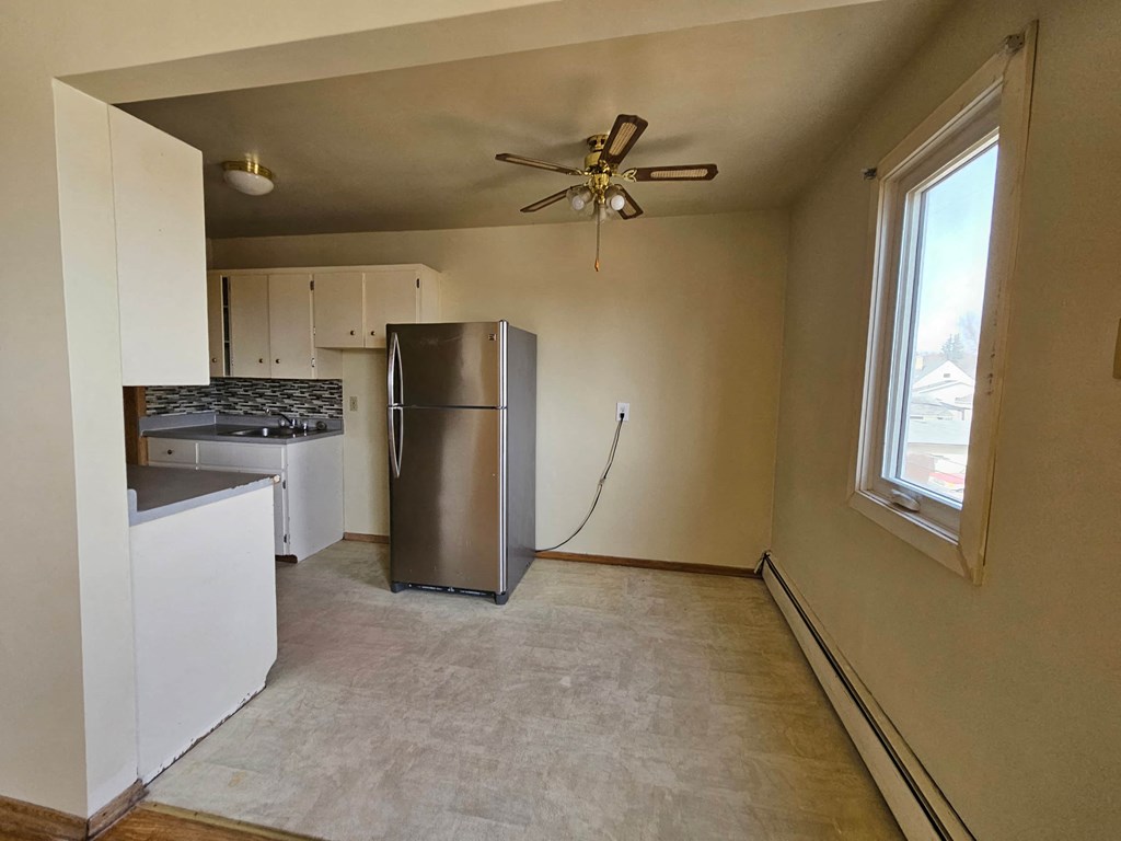 A kitchen with a refrigerator, stove, and cabinets.