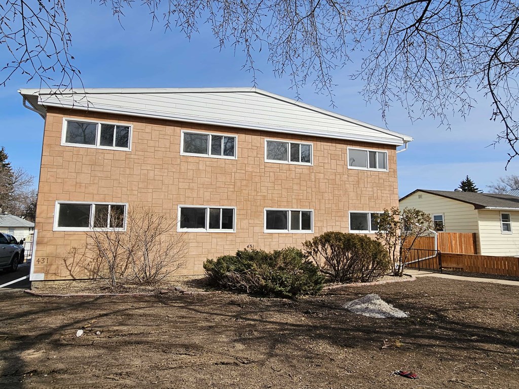 A brown house with a white roof and a white car parked in front.