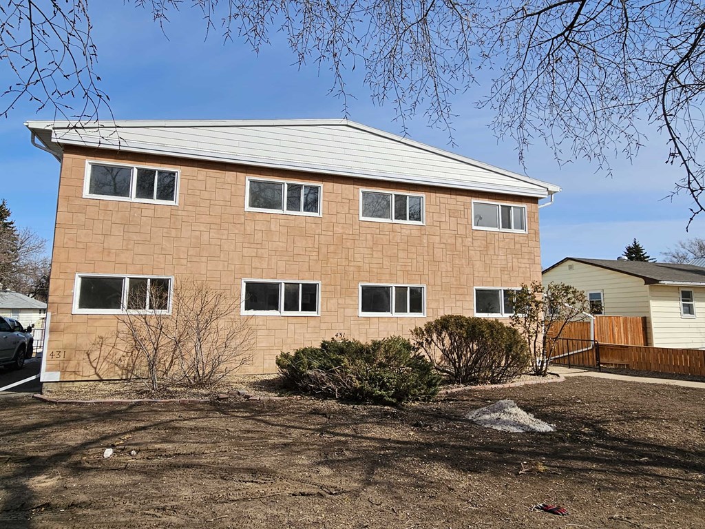 A brown house with a white roof and a white car parked in front.