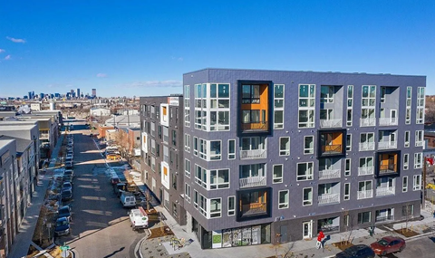 A modern apartment building with a parking lot in front.
