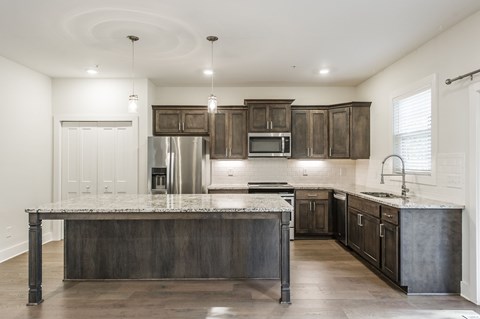 A modern kitchen with dark wood cabinets and a large island.