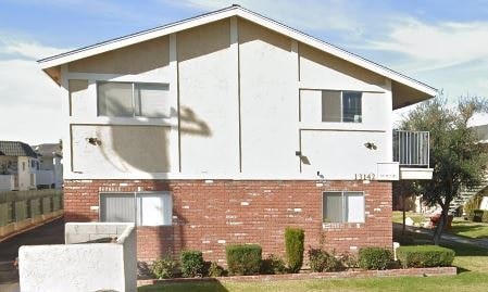A two-story building with a white exterior and a brick base.