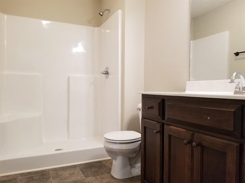 A white toilet sits in a bathroom next to a white sink.