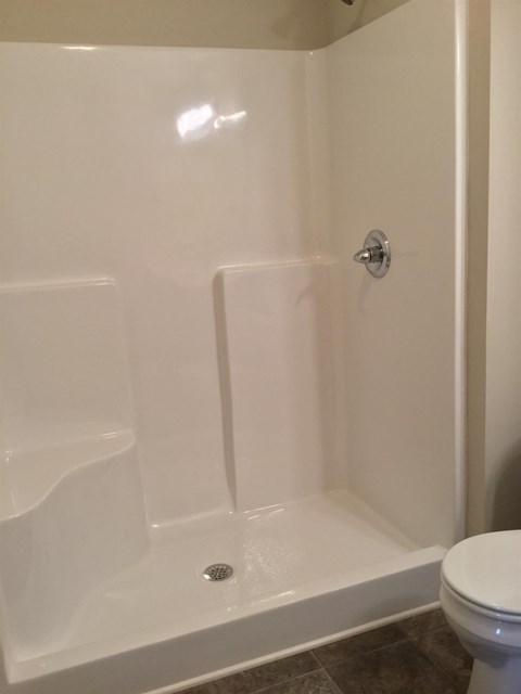 A white toilet sits next to a white bathtub in a bathroom.