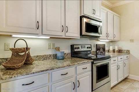 A kitchen with white cabinets and a granite countertop.