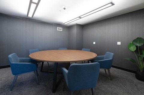 A conference room with a round table and blue chairs.