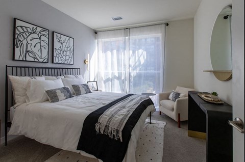 A bedroom with a large bed and a chair.