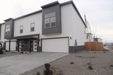 A modern two-story building with a garage door and a gravel driveway.
