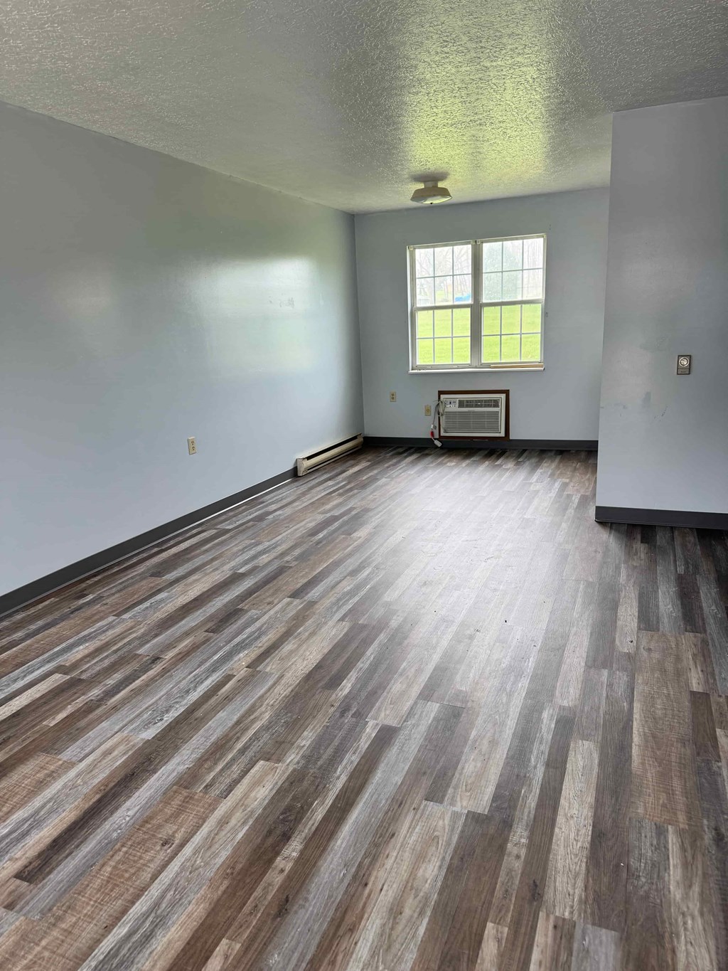 A room with wooden flooring and a window.