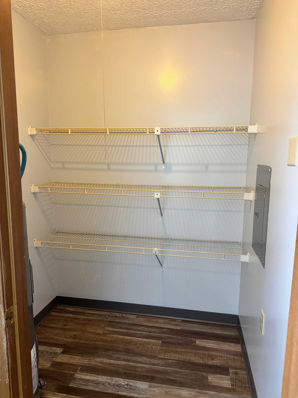 Empty shelves in a white room with wood flooring.