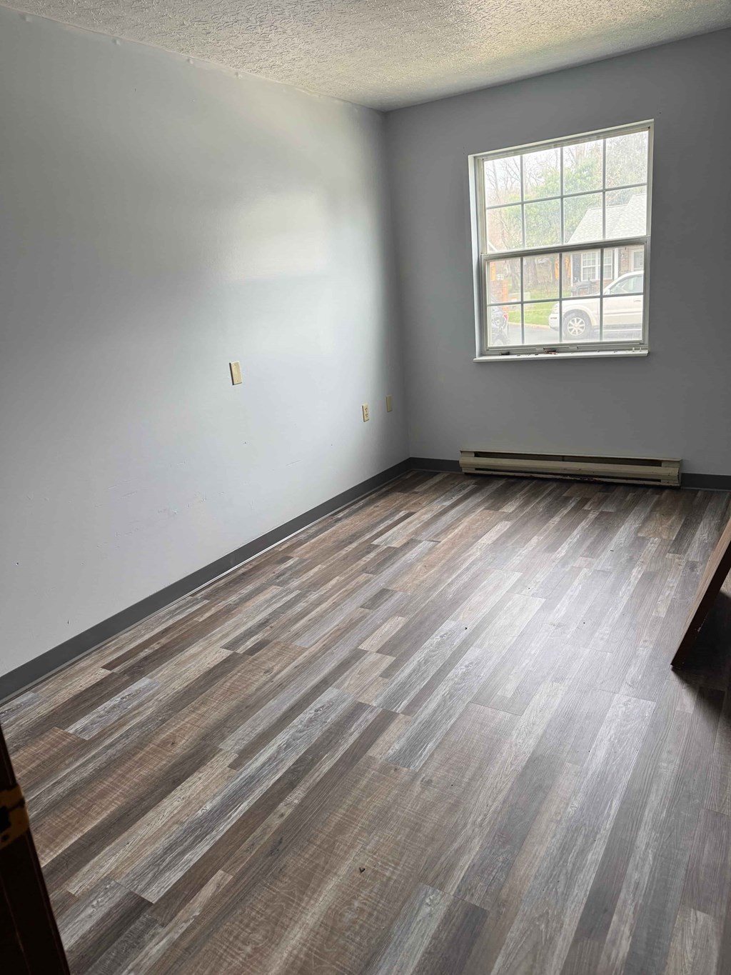 A room with a window and wooden flooring.