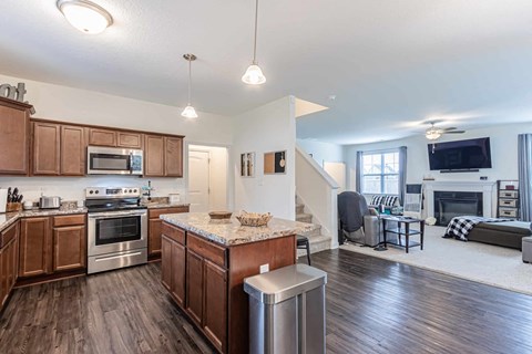 A modern kitchen with wooden cabinets and a marble island.
