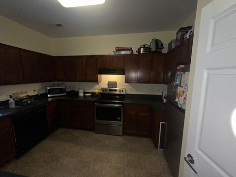 A kitchen with brown cabinets and black countertops.