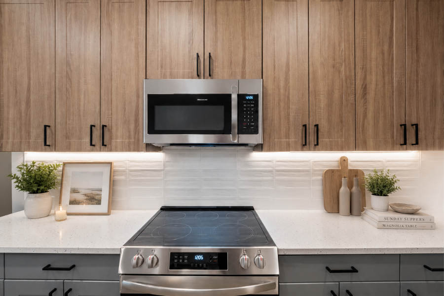 A modern kitchen with a stainless steel oven and microwave above a black induction cooktop.