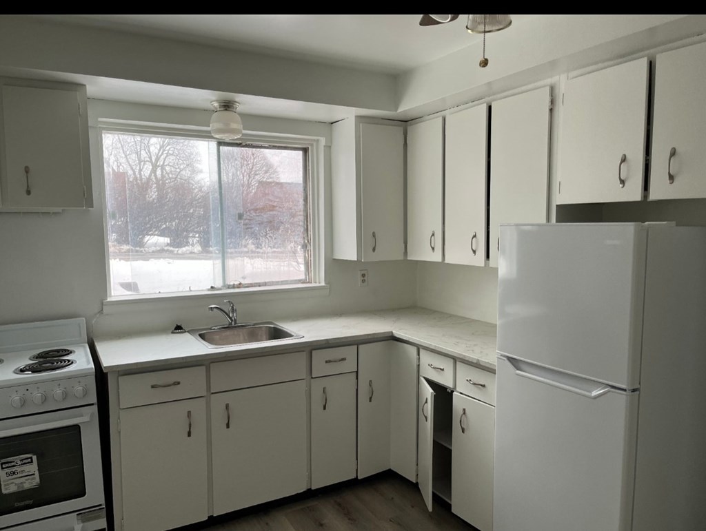 A kitchen with white cabinets and appliances.
