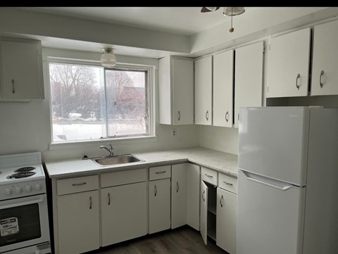 A kitchen with white cabinets and appliances.