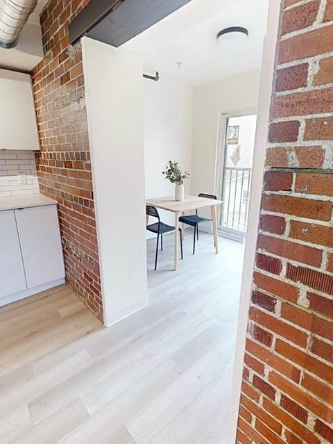 A room with a brick wall and a white cabinet.
