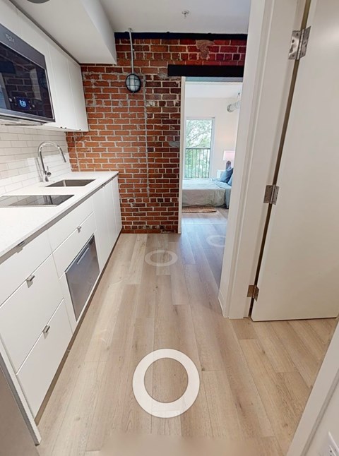 A kitchen with white cabinets and a brick wall.