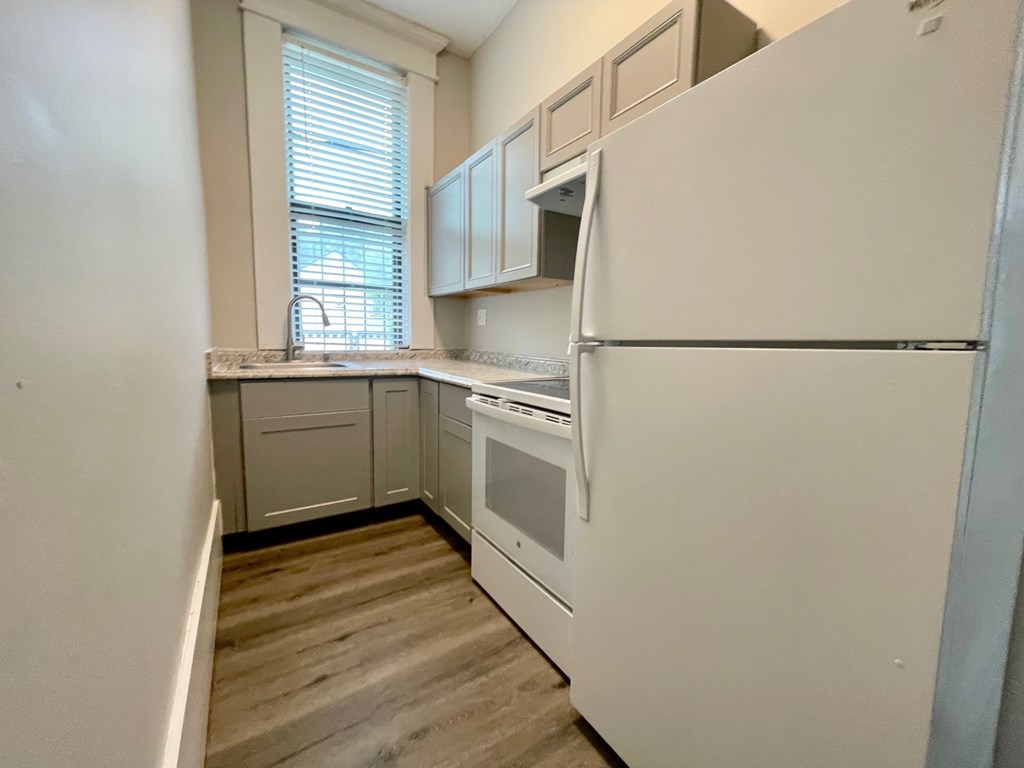 A kitchen with white appliances and wooden floors.