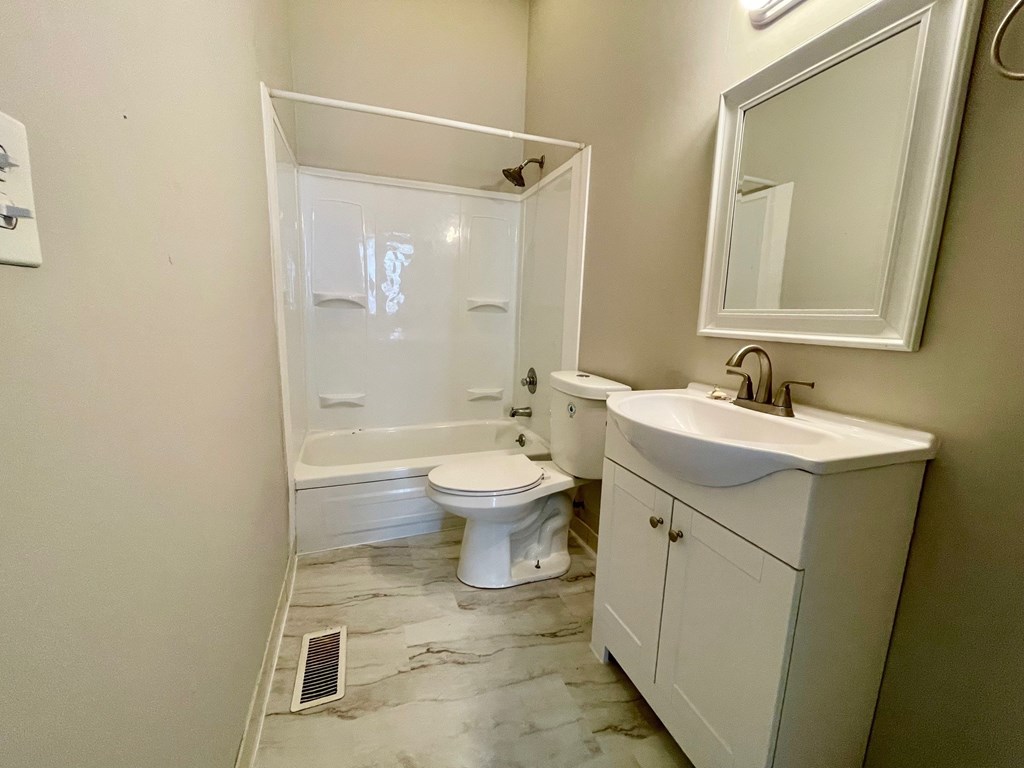 A white bathroom with a toilet, sink, and mirror.