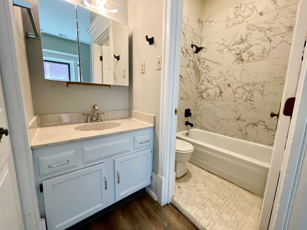 A bathroom with a marble wallpaper and a white bathtub.