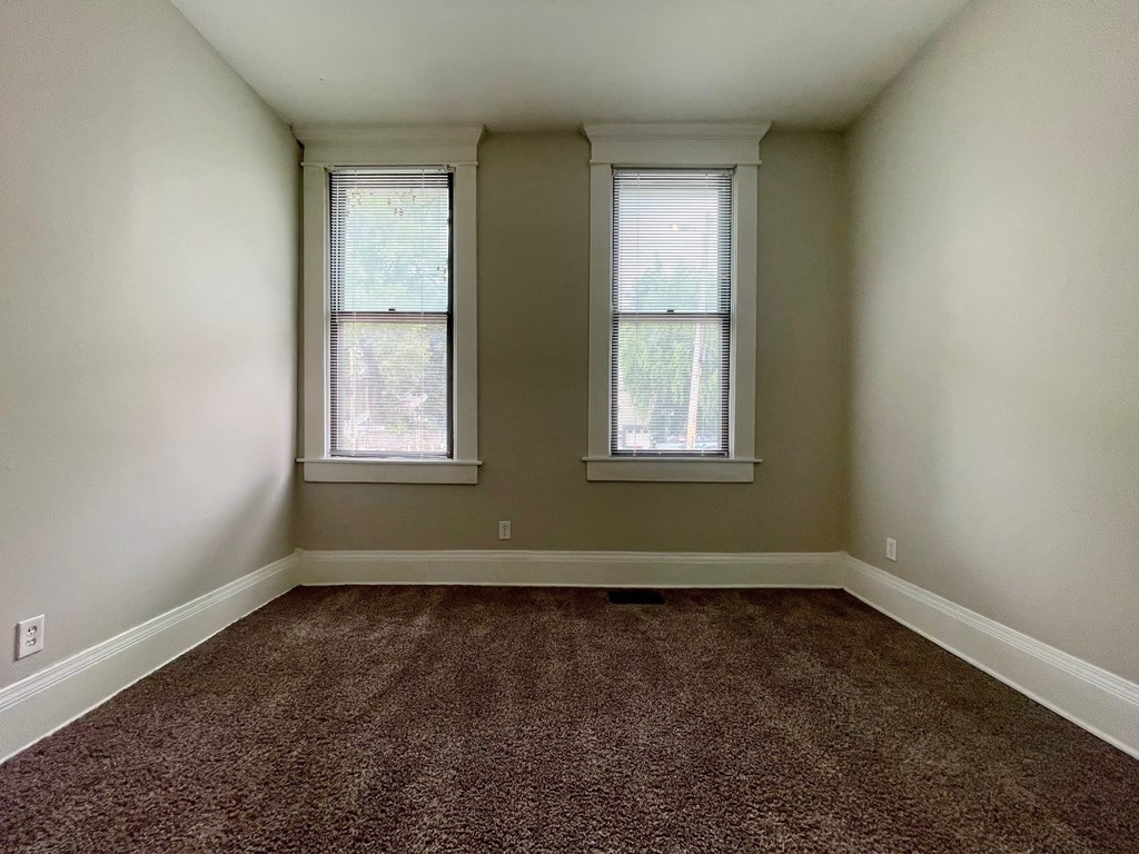 A room with two windows and carpeted floor.