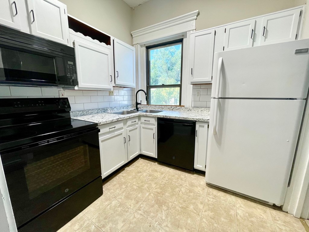 A kitchen with black appliances and white cabinets.
