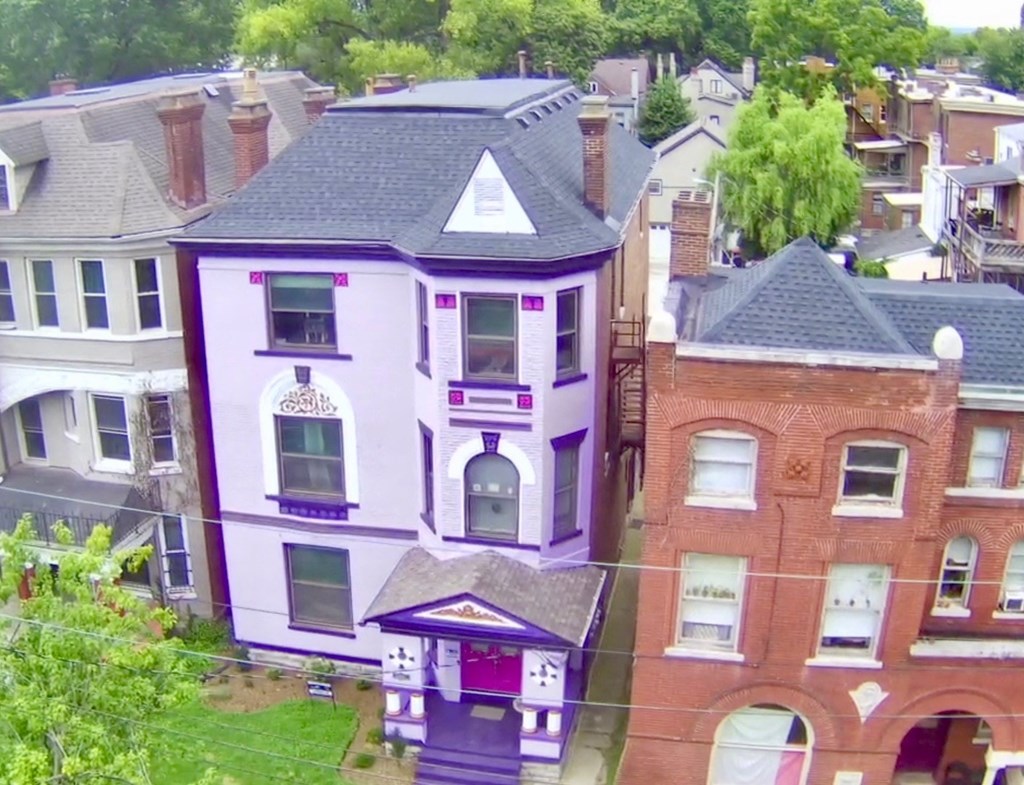 A purple house with a black roof is in the foreground.