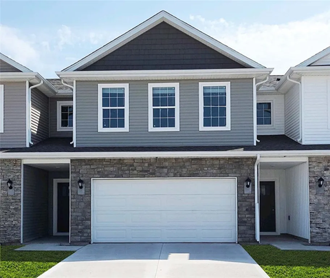 A modern house with a grey and white exterior and a large garage door.
