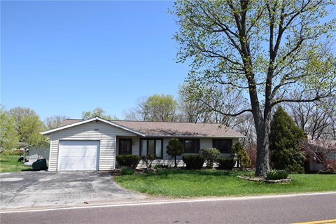 A house with a garage and a tree in front.