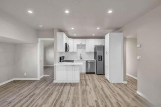 A kitchen with white cabinets and a wooden floor.