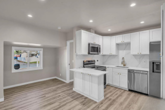 A kitchen with white cabinets and a wooden floor.