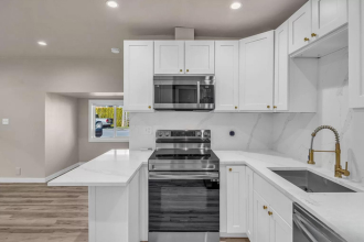 A modern kitchen with white cabinets and appliances.