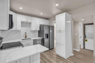 A modern kitchen with white cabinets and a marble countertop.